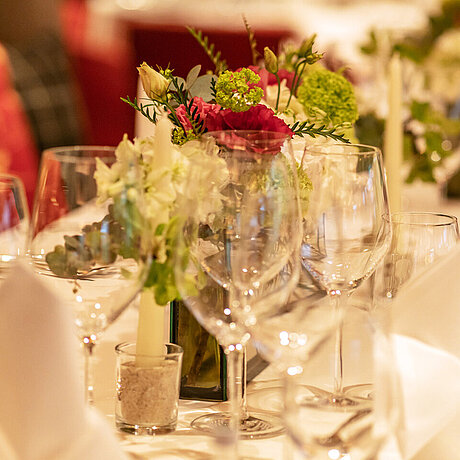 Ein Tisch im Löwen Hotel Montafon ist festlich mit Blumen und Weingläsern eingedeckt