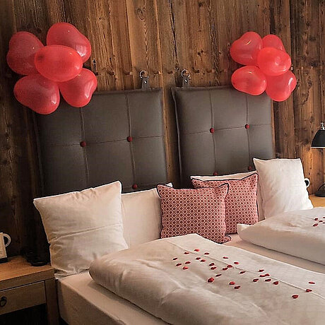 In der Hochzeitssuite des Löwen Hotel Montafon hängen über dem Doppelbett herzförmige Luftballons