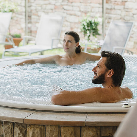 Ein Paar entspannt im heißen Whirlpool im Wellnesshotel in Vorarlberg
