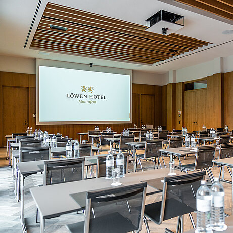 Modern conference hall with chairs and tables and a large screen at the Löwen seminar hotel