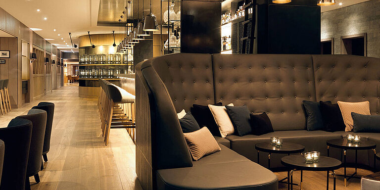Die Lounge im Löwen Hotel Montafon mit runden Tischen, auf welchen Teelichter stehen