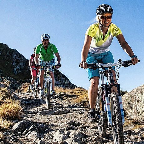 Drei Radfahrer folgen einem steinigen Trail im Gebirge nahe des Löwen Hotel Montafon