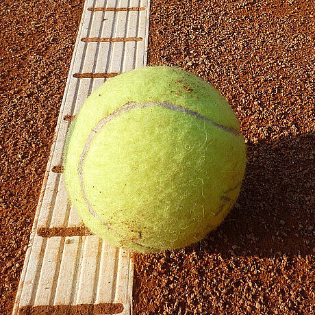 Ein Tennisball liegt einsam auf der Bodenmarkierung eines Tennisplatzes nahe des Löwen Hotel Montafon 
