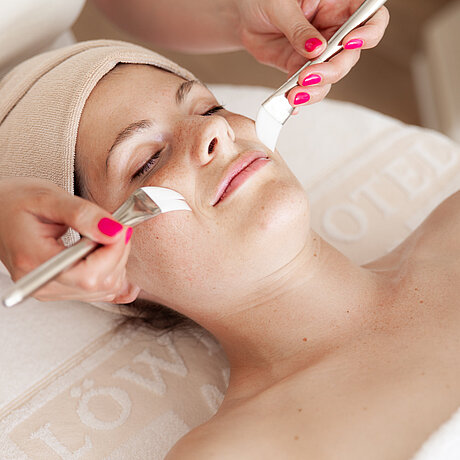 Eine Frau im Wellnessbereich des Löwen Hotel Montafon erhält eine kosmetische Gesichtsbehandlung
