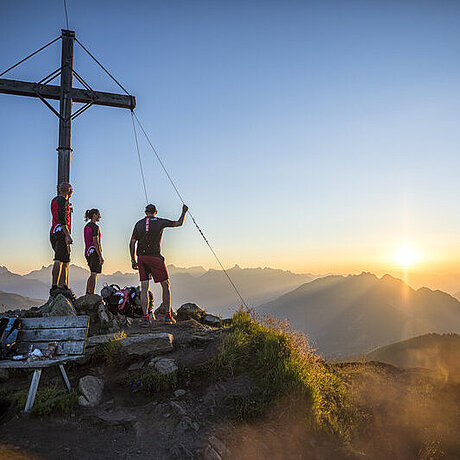 Personen stehen auf dem Muttjoechle Berggipfel neben einem großen Kreuz