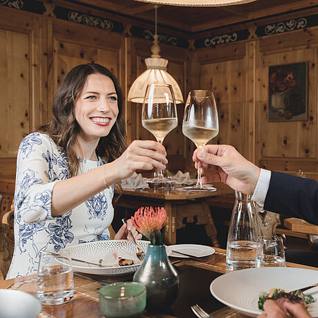 Ein Paar diniert zusammen in der Stube des Löwen Hotel Montafon und genießt dabei kühlen Weißwein
