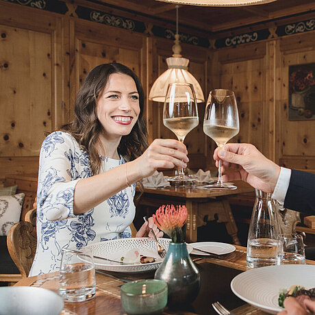 Ein Gästepaar sitzt am Esstisch im Löwen Hotel Montafon und stößt zu einem besonderen Anlass an