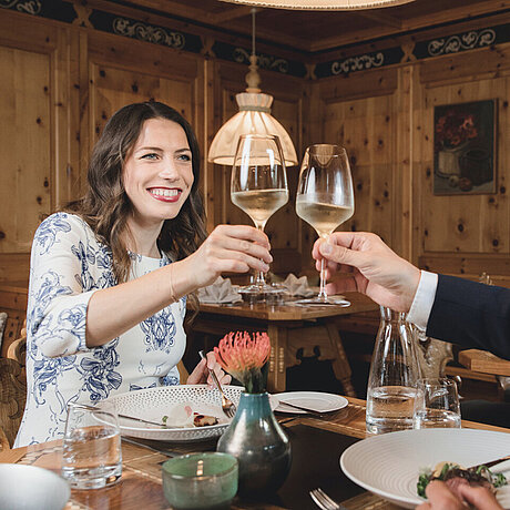 Eine Dame im Restaurant des Löwen Hotel Montafon genießt beim Abendessen ein Glas Weißwein