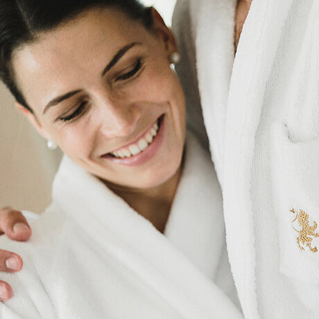 Ein Gast trägt den Bademantel des Löwen Hotel Montafon und lehnt sich an ihren Partner