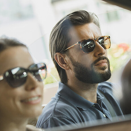 Ein Paar genießt eine Autofahrt auf der Silvretta Hochalpenstraße im Cabriolet