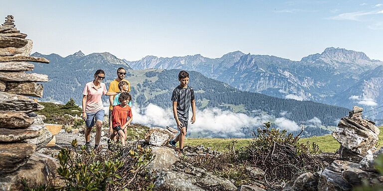 Eine Familie beim Wandern mit atemberaubenden Ausblick auf das Bergmassiv der Silvretta.