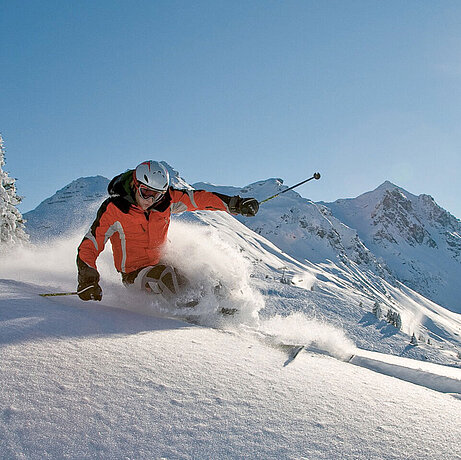Ein Skifahrer fährt bei einer Abfahrt durch den leichten Pulverschnee im Skigebiet nahe des Löwen Hotel Montafon