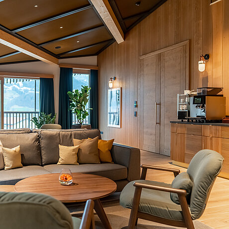 Living area with comfortable upholstered furniture and a large balcony with a view of the Montafon mountain panorama